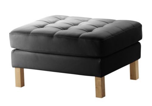 Ikea Karlstad ottoman in black leather with boring wood legs. Simple, timeless, classic..... Except for those ugly legs. 