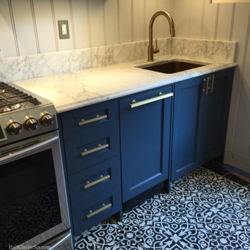 I am completely in love with how everything complements each other. The Stiffkey Blue cabinets, black and white cement tile floor, honed Carrara counters, beadboard walls, and brass hardware. 